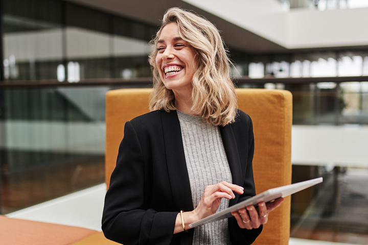 Lachende Frau hält Tablet in der Hand