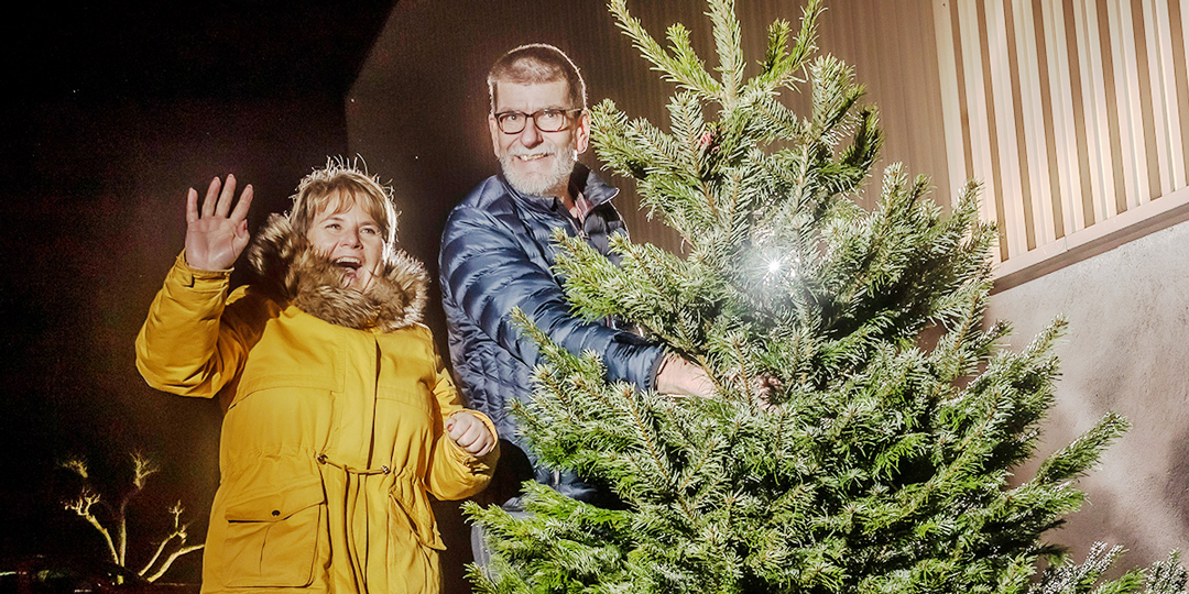 Mann und Frau lachend mit Weihnachtsbaum während Weihnachtsbaum-Aktion für Interflex-Kunden