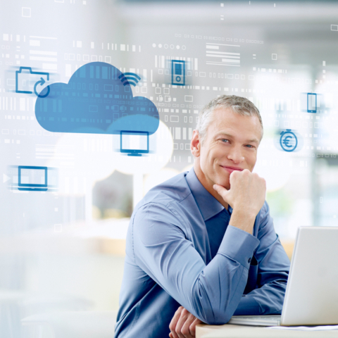 Lächelnder Mann am Schreibtisch mit Laptop