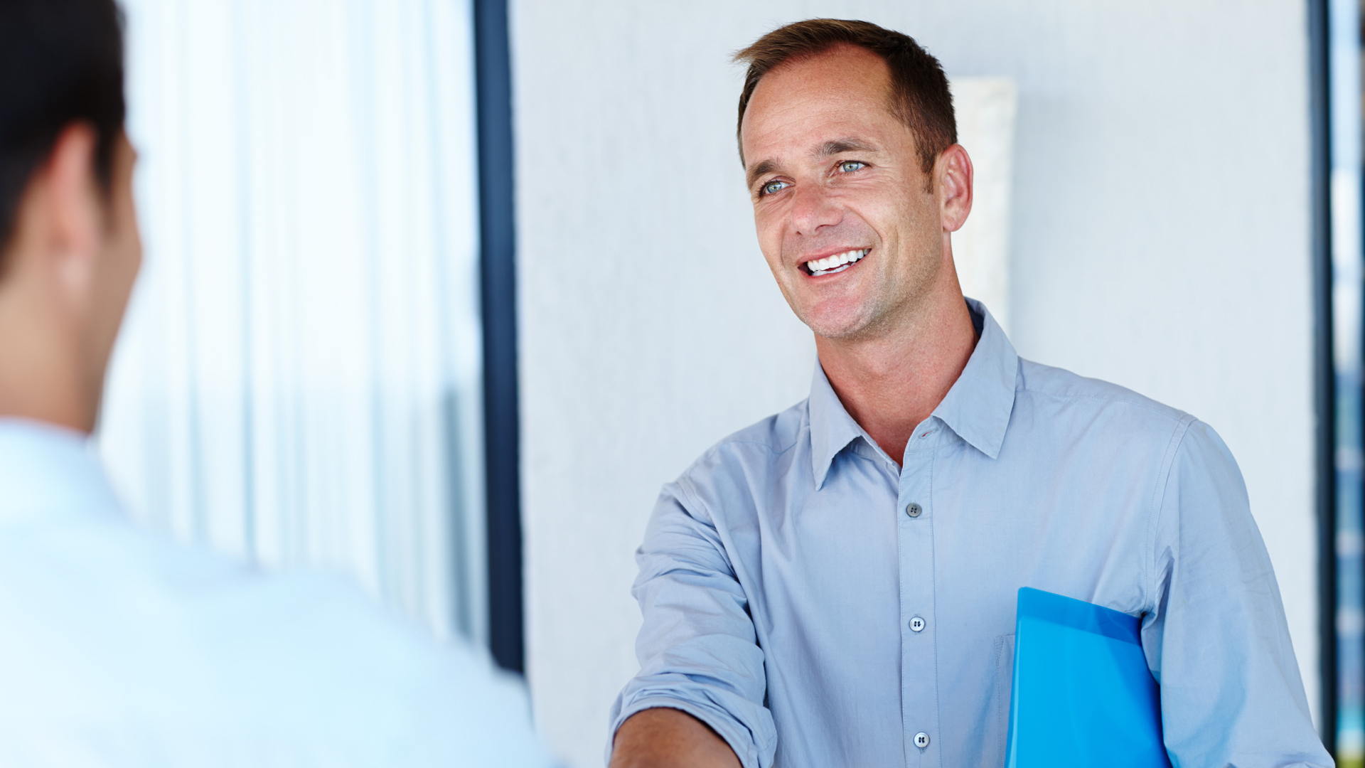 Mann reicht lächelnd die Hand zur Begrüßung