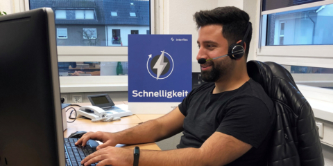 Interflex-Service-Mitarbeiter mit Headset am Schreibtisch